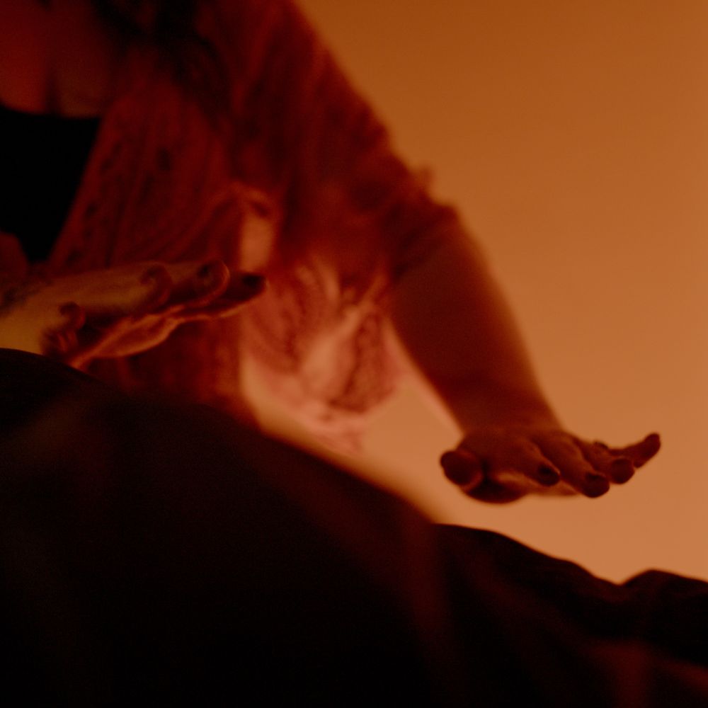 Alicia's hands open above a client lying on the sound bed