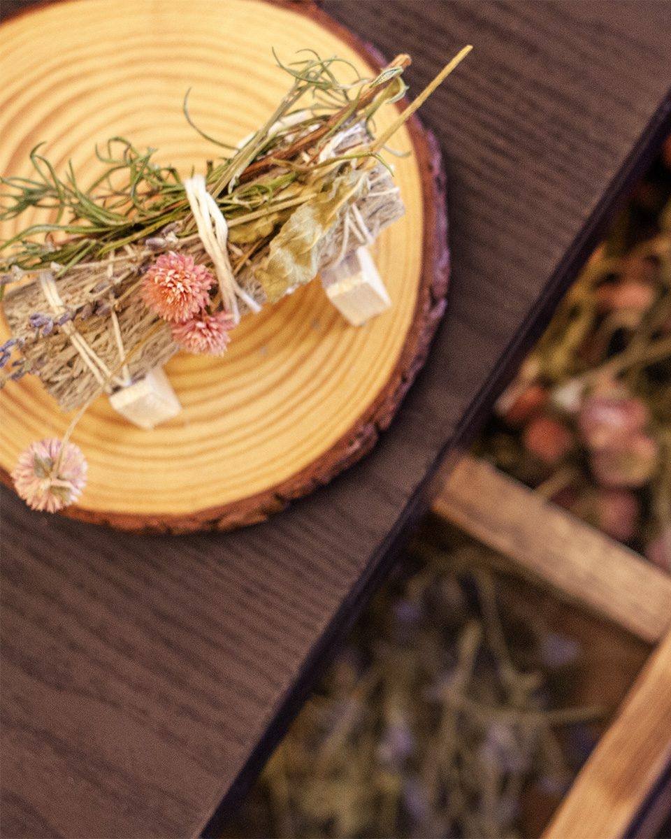 A handmade sage bundle with dried flowers on a wood slice