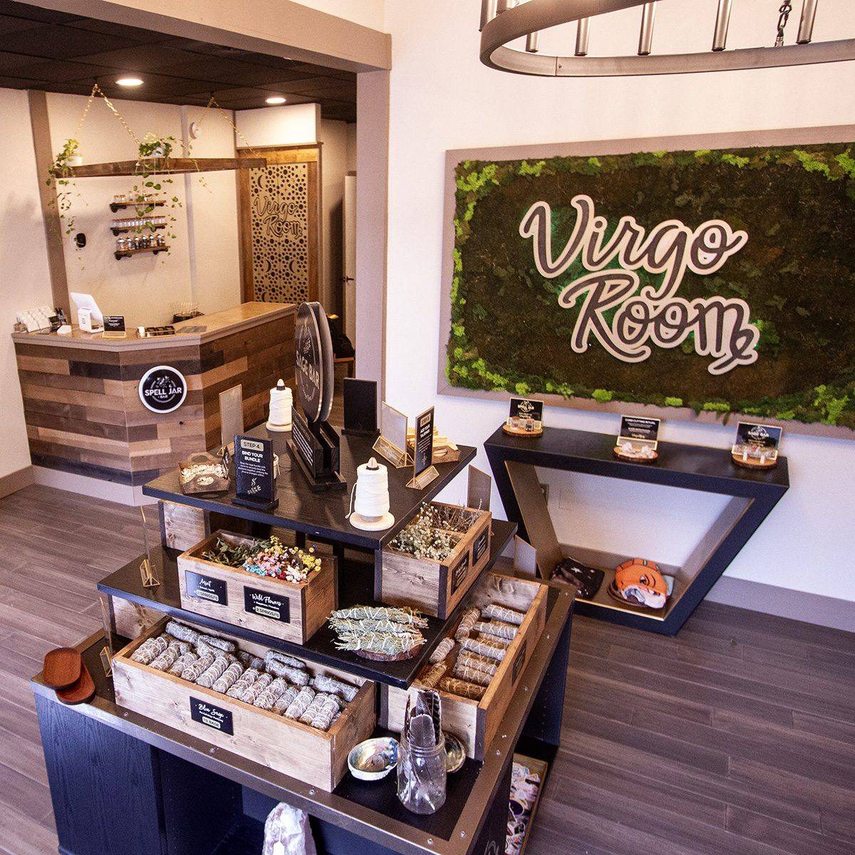 Inside Virgo Room: the moss wall sign, the Spell Jar Bar, and a table of sage bundles